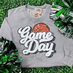 May include: A gray sweatshirt with a sequined basketball and the words "Game Day" in white and black.