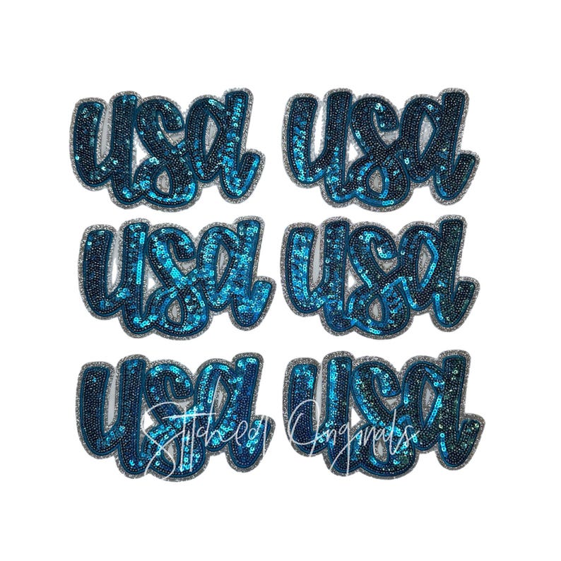 May include: Six teal sequined patches in a cursive font spelling "USA". The patches have a dark blue outline and are arranged in two rows of three. The bottom row includes the text "Stitched Originals".