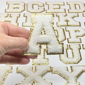 May include: White felt letters with gold glitter trim. The letters are in uppercase and include A, B, C, D, E, F, H, I, K, P, T, U, V, X, and Y.