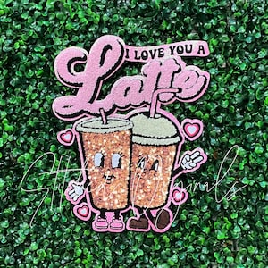 May include: Pink glitter applique with the text "I love you a Latte" and two cartoon coffee cups holding hands.