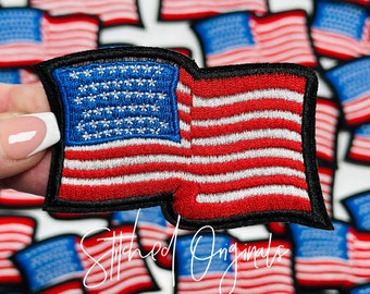 May include: A close-up of a red, white, and blue embroidered American flag patch. The patch is surrounded by other similar patches, all of which are arranged in a grid pattern. The text "Stitched Originals" is visible in the lower right corner of the image.