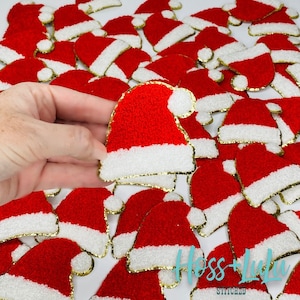 May include: Red and white Santa hat patches with gold trim. The patches are made of a textured material and are scattered across a white surface. One patch is held in a hand. The image includes the text "Hoss + Lulu STITCHED".
