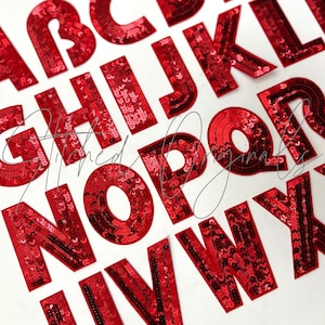 May include: Red sequin alphabet letters on a white background. The letters are in a bold, sans-serif font and are densely covered in shiny red sequins. The letters are arranged in a scattered layout, with some partially visible.