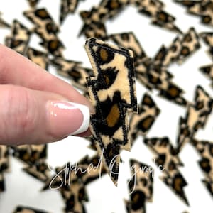 May include: A brown and black leopard print lightning bolt shaped iron-on patch. The patch is made of soft, fuzzy fabric.