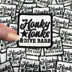 May include: A white square patch with black embroidered text that reads "Honky Tonks & Dive Bars". The text is in a stylized font with a star above the word "Tonks".