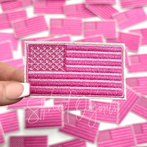 May include: A pink and white embroidered American flag patch. The flag is surrounded by other pink and white embroidered American flag patches.