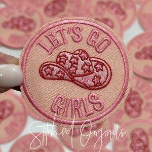May include: Pink embroidered patch with a pink cowboy hat and the text "Let's Go Girls".