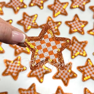 May include: Orange and white checkered star-shaped iron-on patches with gold glitter trim.