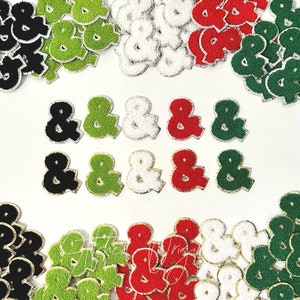 May include: Assortment of felt ampersand patches in black, green, white, and red. The patches have a gold outline and are perfect for adding a touch of personality to clothing, bags, or other crafts.