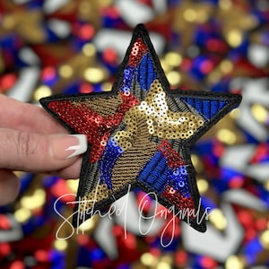 May include: A large, sparkly, five-pointed star patch with red, gold, and blue sequins. The star is sewn onto a black fabric base.