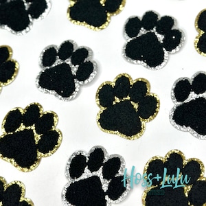 May include: Assortment of black paw print iron-on patches with gold and silver glitter trim. The patches are approximately 1 inch in diameter.