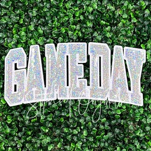 May include: White iron-on patch with the word "GAMEDAY" in sparkly silver glitter letters.
