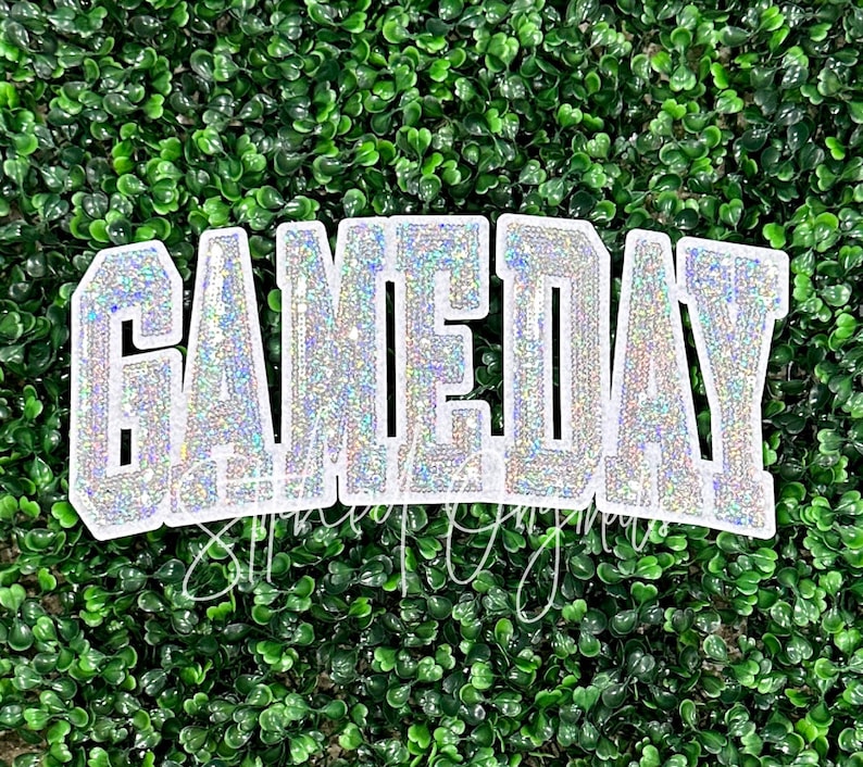 May include: White iron-on patch with the word "GAMEDAY" in sparkly silver glitter letters.