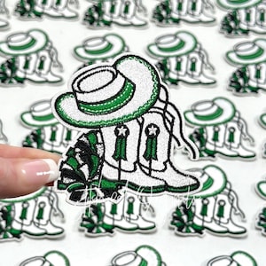 May include: White and green embroidered patch featuring a cheerleader's hat, boots, and pom-poms.