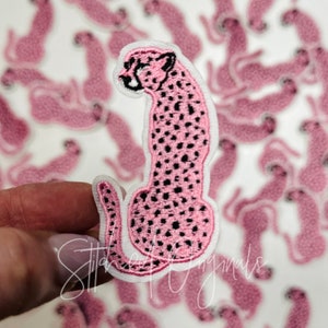 May include: Pink cheetah iron-on patch with black spots. The patch is on a white background with other pink cheetah patches.