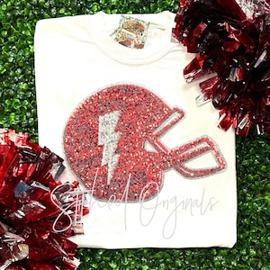 May include: White t-shirt with a red and silver sequined football helmet with a lightning bolt design. The text "Styled Originals" is visible at the bottom of the image.