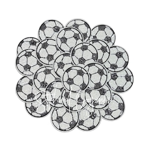 May include: A collection of black and white soccer ball patches. The patches are arranged in a circular pattern, with the soccer balls facing outwards.