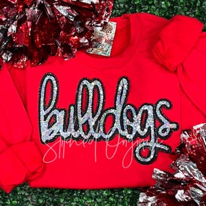 May include: Red sweatshirt with a silver and black sequined "Bulldogs" design.