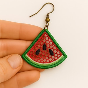 Op de afbeelding: Enkele oorbellen in de vorm van een watermeloen schijfje met een rood, groen en wit geborduurd ontwerp. De oorbel heeft een bronzen haak en een gedetailleerd, open geweven patroon, met drie zwarte zaaddetails.