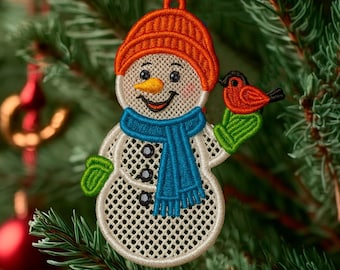 May include: Embroidered snowman Christmas ornament with an orange knit cap, blue scarf, and green mittens. The snowman has a carrot nose and is holding a red bird. The ornament is hanging on a Christmas tree.