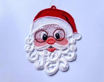 May include: White and red embroidered Christmas ornament featuring a Santa Claus face with a white beard and a red hat.