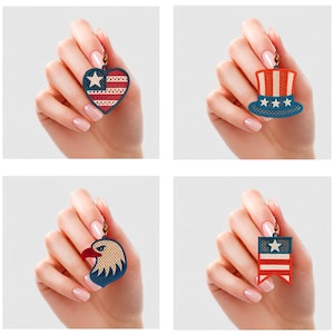 Puede incluir: Cuatro pendientes de temática patriótica. Uno tiene forma de corazón con una estrella y rayas, otro es un sombrero de copa, un tercero es una cabeza de águila y el último es un diseño de bandera. Cada pendiente tiene un gancho dorado.