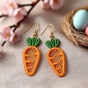 May include: A pair of carrot-shaped earrings with gold-colored hooks. The earrings feature orange embroidered carrot bodies with green embroidered tops. The background includes a nest with eggs and pink flowers.