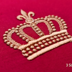 May include: Gold embroidered crown design on a red fabric background. The crown has a pointed top and three arches. The text "3 Sizes" is visible at the bottom of the image.