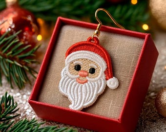 May include: A Santa Claus earring with a red hat and white beard, displayed in a red gift box. The earring has a gold hook and is set against a festive background with Christmas ornaments and greenery.