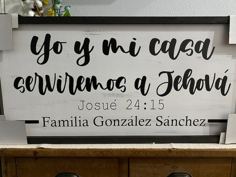 May include: A white wooden sign with black lettering that reads "Yo y mi casa serviremos a Jehov&aacute; Josu&eacute; 24:15 Familia Gonz&aacute;lez S&aacute;nchez".