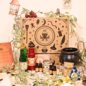 May include: A brown box with a black and white illustration of a potion bottle and the text "The Potion Lab". The box is filled with various potion bottles, a cauldron, and other magical items. The box is surrounded by greenery and fairy lights.