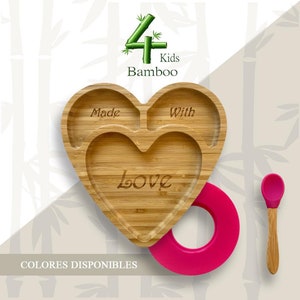 Puede incluir: Un plato de bambú en forma de corazón con las palabras "Made With Love" grabadas. Tiene un anillo rosa brillante adjunto y una cuchara pequeña. El logotipo "4 Kids Bamboo" está en la parte superior.