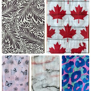 May include: A selection of decorative paper napkins with diverse patterns. One displays a brown floral design, another showcases red maple leaves on a wood-effect background, and a third features butterflies and dragonflies on a pink backdrop.