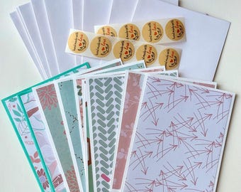 May include: A set of blank greeting cards with envelopes and stickers. The cards have various patterns including floral, geometric, and abstract designs. The stickers are round and have the text "hand made with love" in red and white.