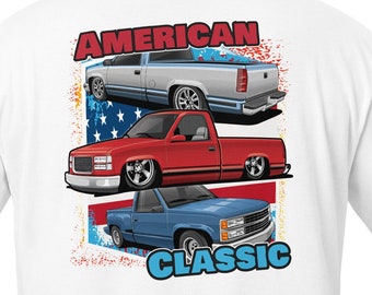 May include: White t-shirt featuring a graphic of three classic American trucks in front of an American flag with the text "AMERICAN CLASSIC" printed on the back.