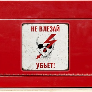 May include: A red metal toolbox with a black handle and silver latches. A sticker on the front features a skull with a lightning bolt and the text "DO NOT TOUCH, WILL KILL!" An American flag sticker is on the side.