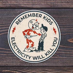 May include: A round, white sticker with a red and black cartoon character holding a knife. The sticker has the text "Remember Kids Electricity Will Kill You" around the edge.