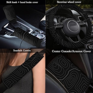 Peut inclure: Ensemble d'accessoires int&eacute;rieurs de voiture noirs. Comprend un pommeau de levier de vitesses et un couvre-frein &agrave; main, un couvre-volant, des couvre-ceintures de s&eacute;curit&eacute; et un couvre-accoudoir central. Motif topographique blanc sur fond noir.