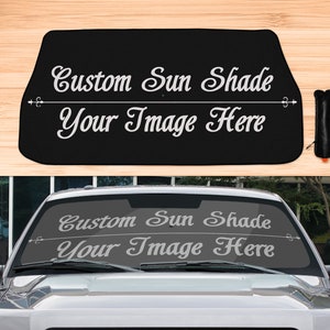 Puede incluir: Parasol personalizado negro para el parabrisas de un coche con el texto "Custom Sun Shade Your Image Here" en blanco.