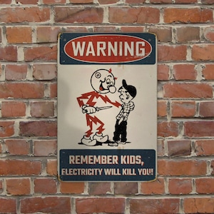 May include: A rectangular metal sign with a red and blue border, mounted on a brick wall. The sign features a cartoon illustration of a lightning bolt character holding a knife, threatening a boy. Text on the sign reads "WARNING" and "REMEMBER KIDS, ELECTRICITY WILL KILL YOU!"