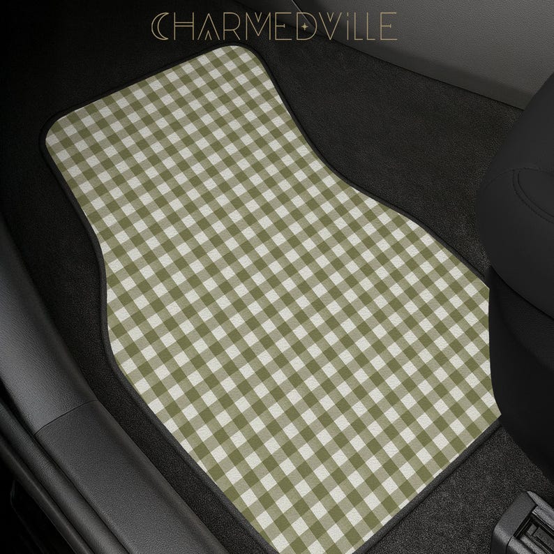 May include: A car floor mat featuring a sage green and white gingham check pattern. The mat has a black border and is positioned in a vehicle footwell. The text CHARMEDVILLE is visible at the top center of the image in a thin, gold font.