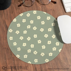May include: A round mouse mat with a green background and a repeating pattern of white flowers.
