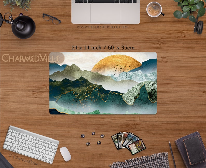 May include: A green, gold, and white mountain landscape with a golden sun rising over the peaks. The design is printed on a 24 x 14 inch mousepad. The text "www.charmedville.com" is printed in the top right corner of the mousepad.