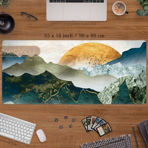 May include: A blue, green, and gold mountain landscape with a golden sun in the background. The design is on a rectangular desk mat measuring 35 x 16 inches or 90 x 40 centimeters.