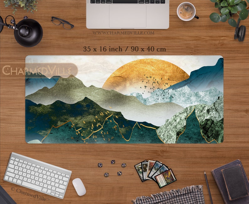 May include: A blue, green, and gold mountain landscape with a golden sun in the background. The design is on a rectangular desk mat measuring 35 x 16 inches or 90 x 40 centimeters.
