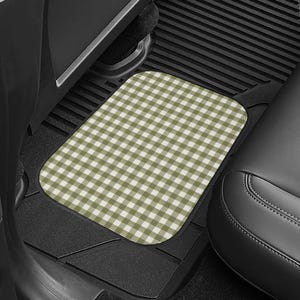 May include: A rectangular car floor mat featuring a sage green and white gingham check pattern. The mat is positioned on the black textured floor of a vehicle interior, situated between the black car seat and the lower door panel trim.