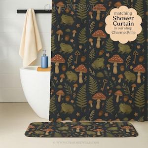 Könnte beinhalten: Dunkelblauer Duschvorhang und passende Badematte mit einem Muster aus Pilzen, Fröschen, Farnen und Schlüsseln. Der Duschvorhang hat eine Textblase mit der Aufschrift "matching Shower Curtain in our shop CharmedVille."