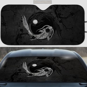 May include: Black and white car sunshade with a yin yang design featuring two koi fish swimming in a circle. The design is set against a background of stylized cherry blossom branches.