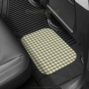 May include: A rectangular car floor mat featuring a sage green and white gingham check pattern. The mat is positioned on the black ribbed floor of a vehicle interior, with the text CHARMEDVILLE visible in the upper portion of the image.