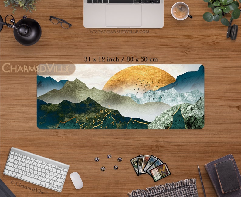 May include: A large, rectangular mousepad with a scenic landscape design. The design features a golden sunset over a mountain range with blue and green hues. The mousepad measures 31 inches by 12 inches, or 80 centimeters by 30 centimeters.